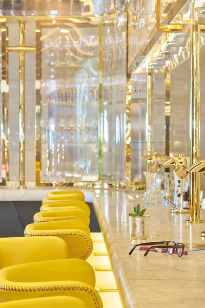 Detalles elegantes de oro y taburetes de cuero amarillo brillante dan a este bar el aspecto de lujo m